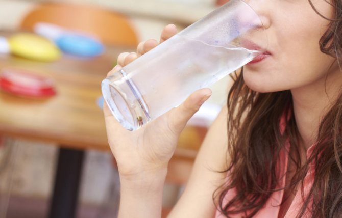 Девушка пьет воду из стеклянного стакана